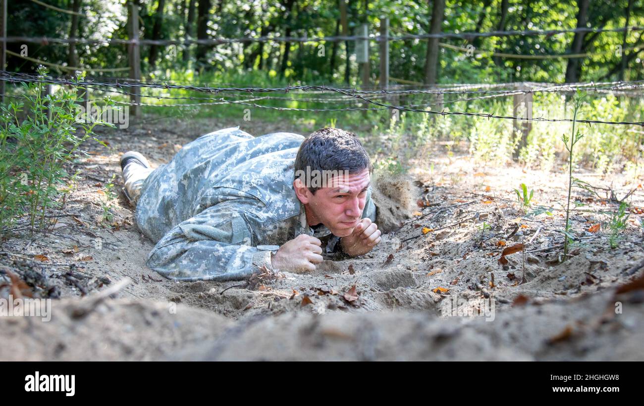 Ejército de EE.UU. SPC. Ben Skelton, Sede Central y Compañía de la Sede, Comando de la Policía Militar de 46th, Guardia Nacional del Ejército de Michigan, crawls bajos bajo el obstáculo de la barriga en el Curso de Confianza en Fort Custer Training Center, Augusta, Michigan, 3 de agosto de 2021. El Cuerpo de Capacitación de Oficiales de Reserva de la Universidad de Michigan Occidental y la Guardia Nacional del Ejército de Michigan se asociaron para albergar un campamento de verano de tres días para 30 participantes. Foto de stock
