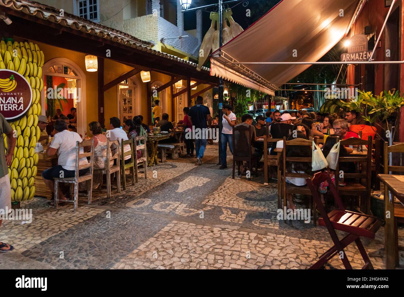 Cena al aire libre con gente comiendo, bebiendo, y caminando en Beco das Garrafas en Prado, Bahia, Brasil. Foto de stock