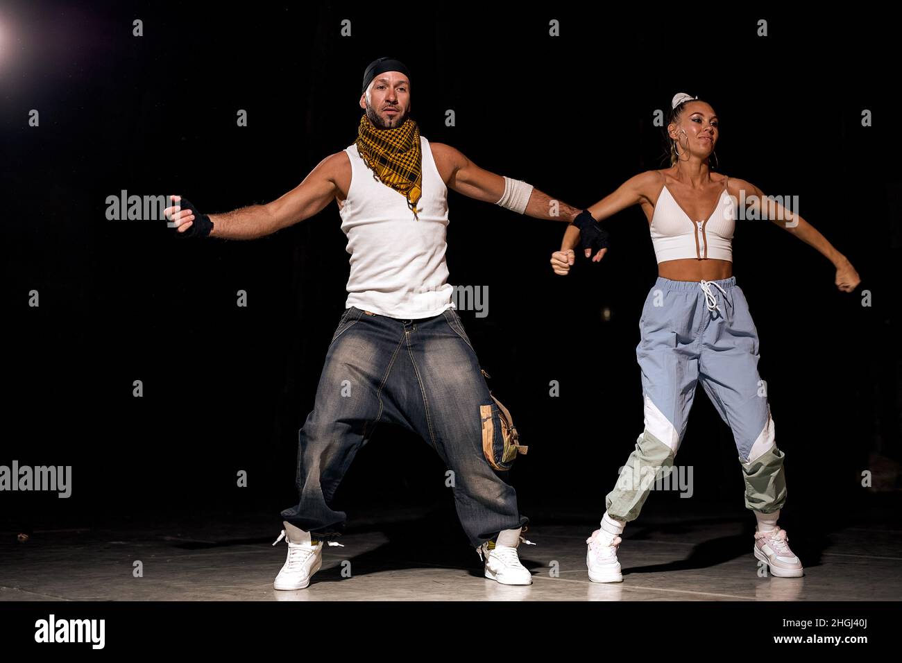 hombre y mujer activos bailando hip-hop con ropa informal sobre fondo negro en la sala de baile luz blanca. Cultura juvenil, movimiento, estilo y Fotografía de stock - Alamy