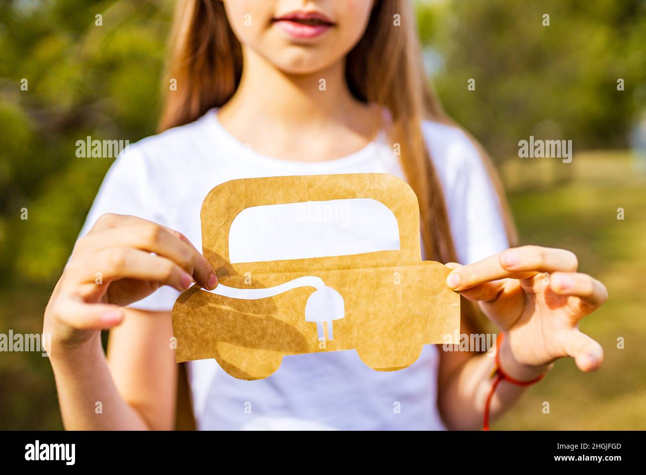 Niña con artesanía creativa hobby papel ambiente de coche, ecológico, ahorrar energía en el parque en el día de verano Foto de stock