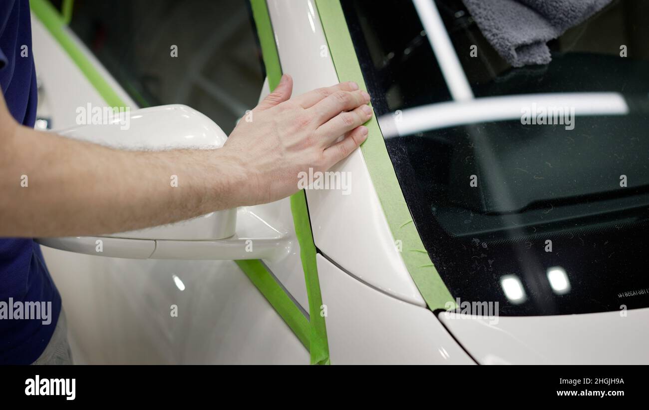 Un hombre pone cinta de vinilo en un coche. Envoltorio de coche con cinta  adhesiva, detalles de coche. Instalación de protección de polímeros para la  pintura de la carrocería del vehículo Fotografía