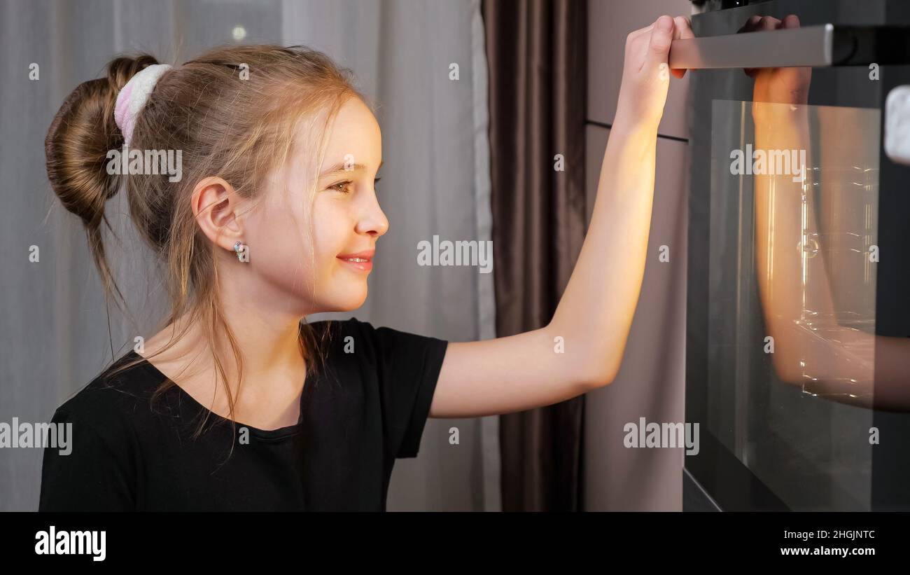 Una niña adolescente espera comida preparándose en la estufa en casa Foto de stock