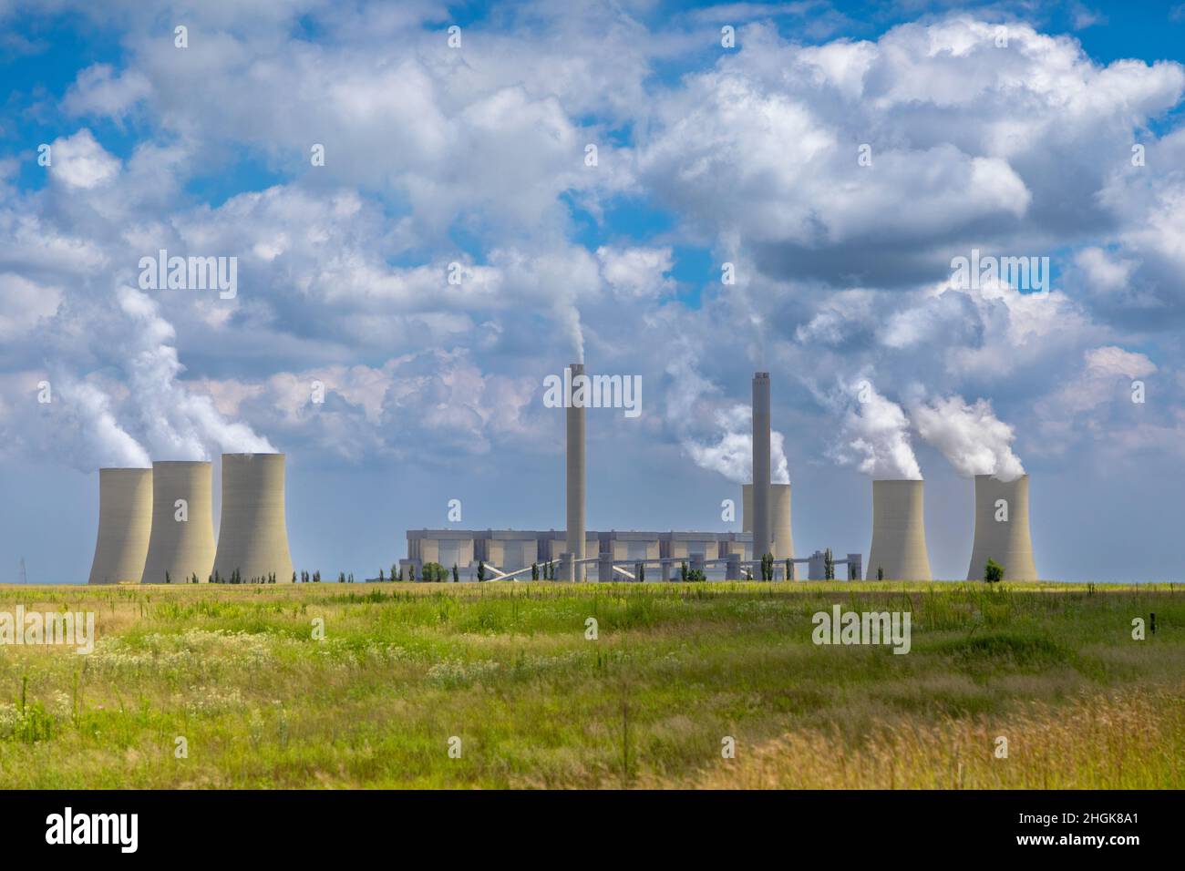 Central eléctrica de carbón en Sudáfrica con humo y vapor que se eleva desde las chimeneas y las torres de refrigeración Foto de stock
