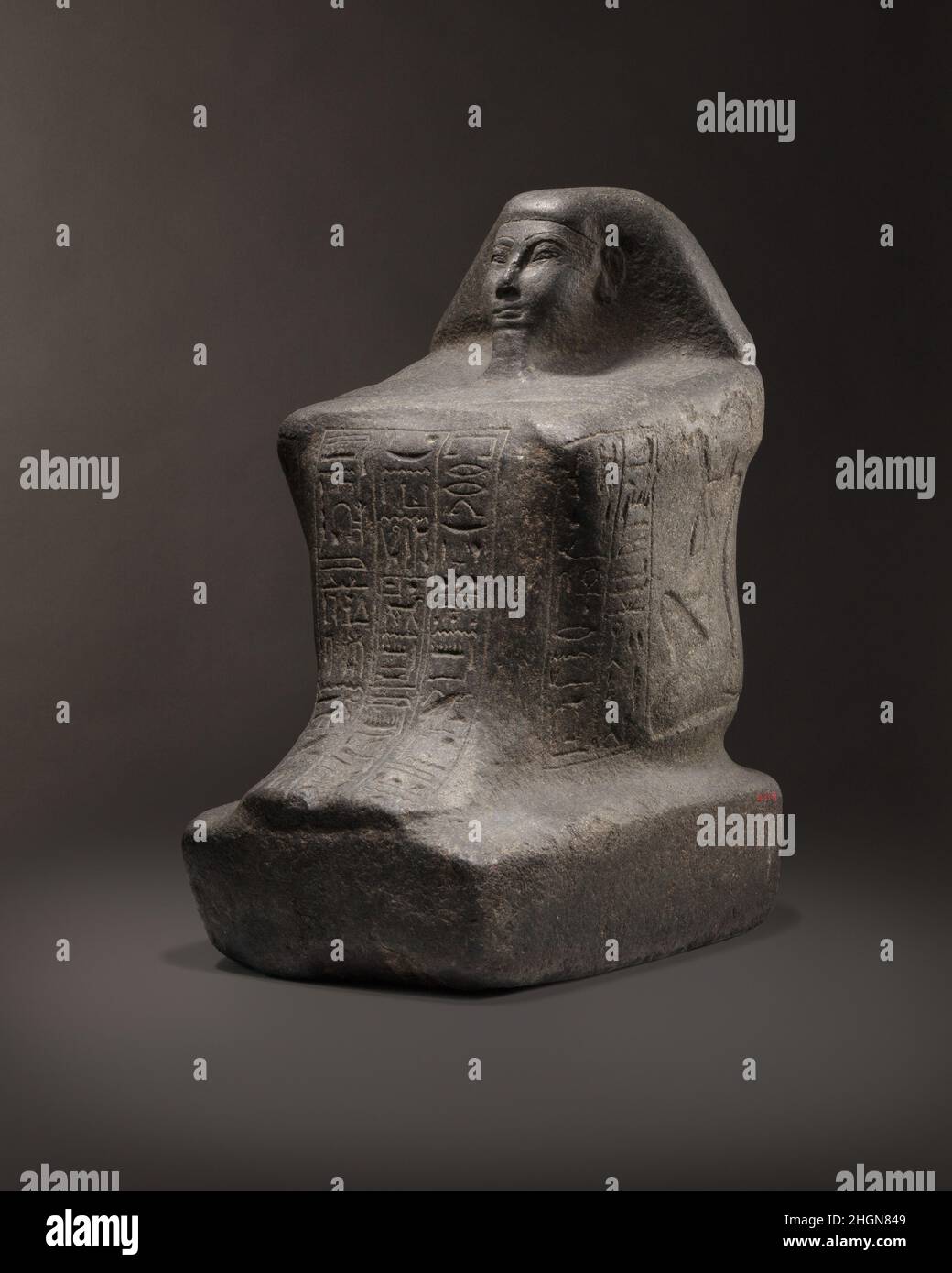 Bloque Estatua de Nedjem Ca. 1184–1153 A.C., el Imperio Nuevo, Ramesside Nedjem ocupó el cargo de 'Padre de dios' en el templo mortuorio del rey Merneptah durante el reinado de Ramsés III; los cartoctos de ambos gobernantes están inscritos en sus hombros. Su estatua lleva inscripciones en los cuatro lados; el panel frontal contiana una oración de ofrenda dirigida a la tríada tebana de Amón, Mut y Khonsu. Las representaciones de la esposa y el hijo de Nedjem aparecen en los lados derecho e izquierdo respectivamente. Nedjem dedicó esta estatua en el templo de la XI Dinastía de Mentuhotpe II en Deir el Bahri para que pudiera participar de th Foto de stock