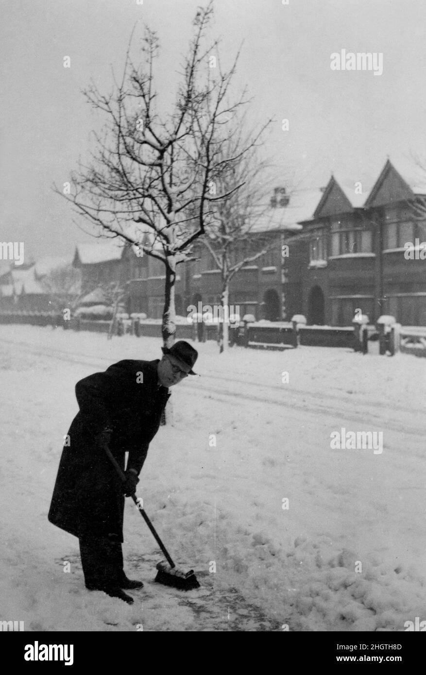 Hombre de edad media despejando el sendero de la nieve en Kirby Road, North End, Portsmouth, Hampshire, Inglaterra, Reino Unido - 1940's. Foto de stock