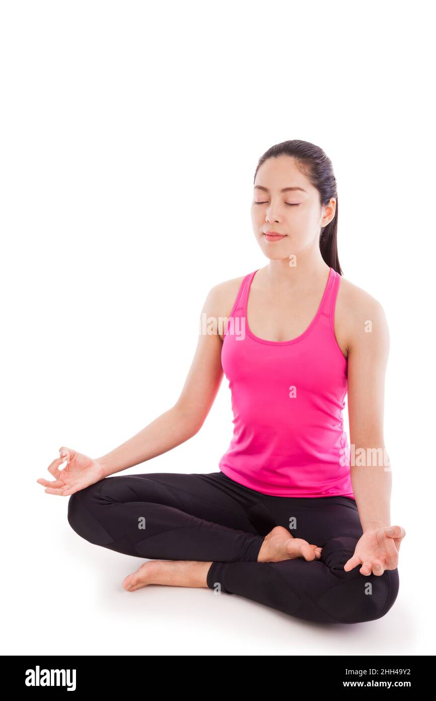 Retrato de una hermosa joven asiática (tailandesa) que practica yoga, sentada en una posición de loto aislada sobre fondo blanco. Espacio para texto de entrada Foto de stock