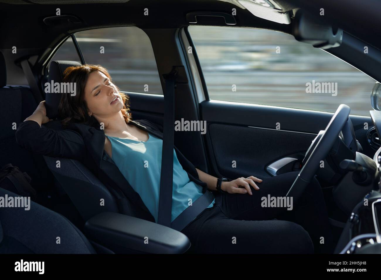 Mujer de negocios cansada durmiendo en un auto autónomo sin conductor Foto de stock
