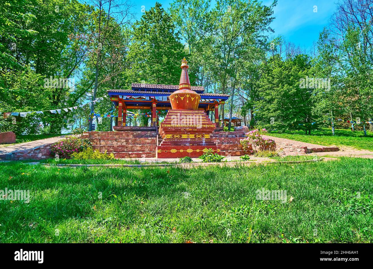 Relájese en el césped del Jardín Tibetano con vistas a la corten roja, decorada con dibujos dorados e inscripciones, el Jardín Botánico de Kiev, Ucrania Foto de stock