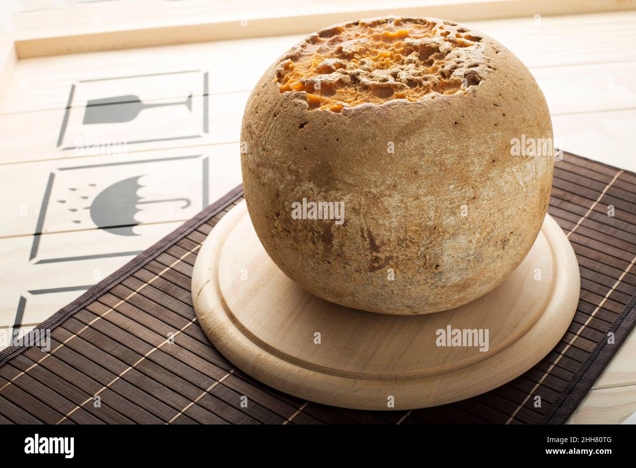 Pan entero de queso Mimolette sobre un plato de madera. Foto de stock