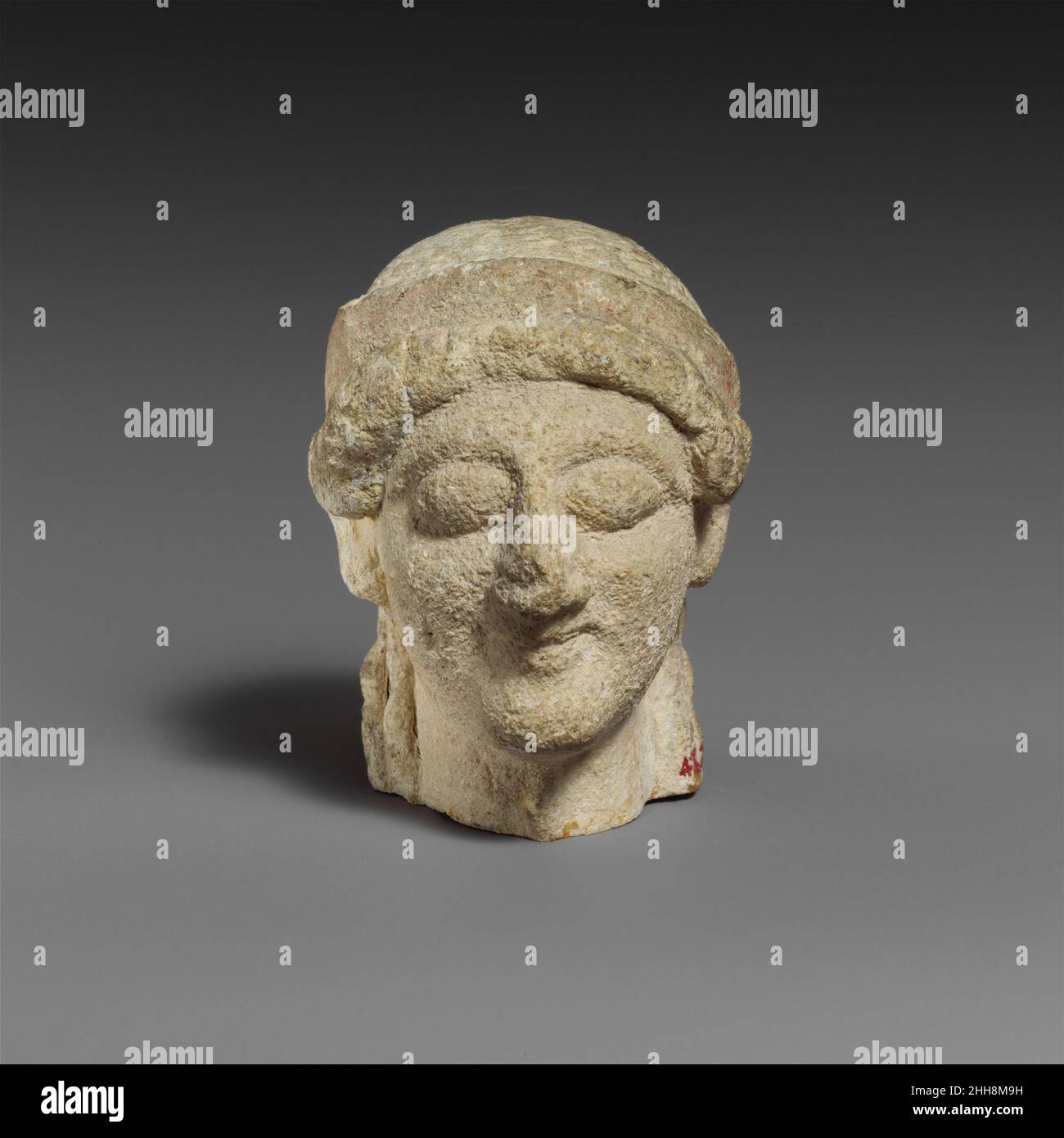 Cabeza de piedra caliza hembra principios del siglo 5th a.C. chipriota La cara tiene una expresión sonriente, ojos salientes, y orejas no articuladas, cada una decorada con una pieza de joyería en forma de vieiras. Cabeza de piedra caliza hembra. Chipriota. Principios del siglo 5th a.C. Piedra caliza. Arcaico. Escultura en piedra Foto de stock