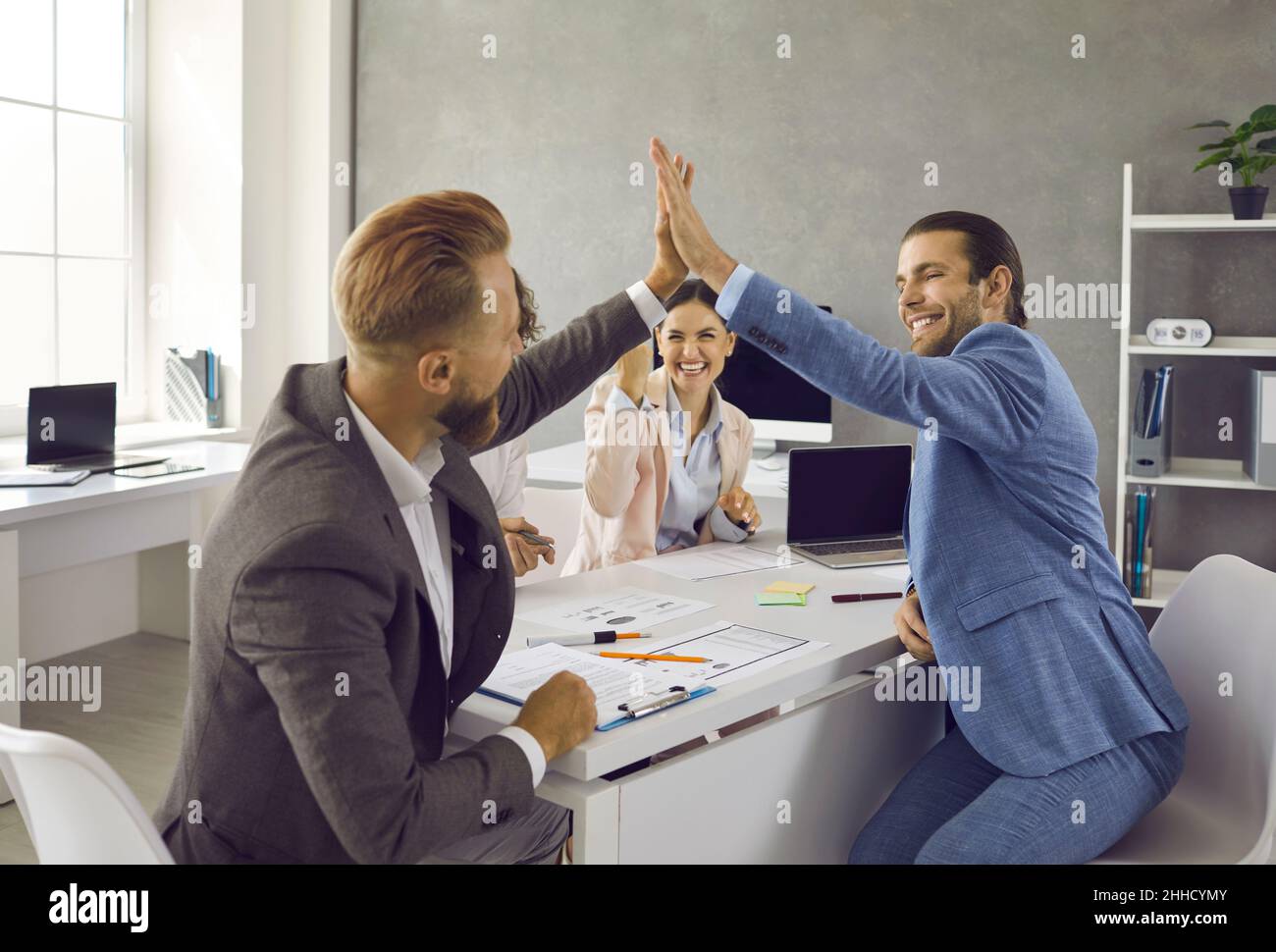 Dos hombres de negocios felices celebran la victoria dando cinco entre sí después del trabajo Bien hecho. Foto de stock