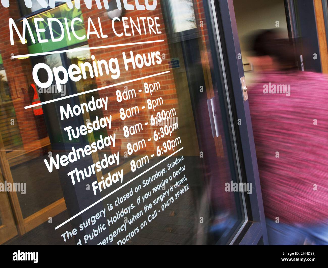 Señalización del tiempo de apertura del nuevo centro de salud en Suffolk con puertas automáticas que se abren cuando el paciente entra en el centro de salud en desenfoque Foto de stock