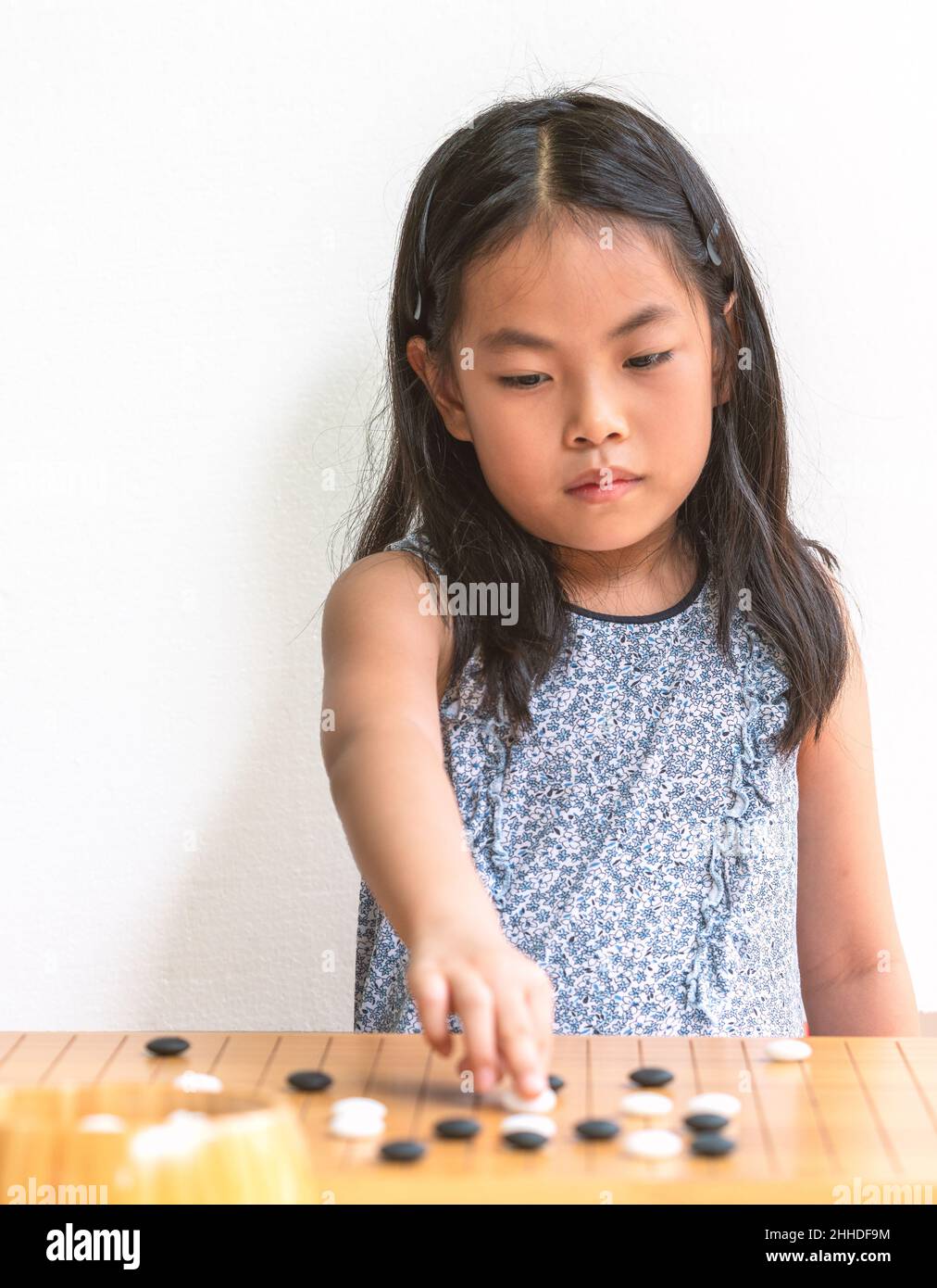 Retrato linda niña asiática juega Go, el juego de mesa japonés o juego de  mesa chino, enfoque en el juego de mesa, fondo de pared blanco, ojos en la  ga Fotografía de