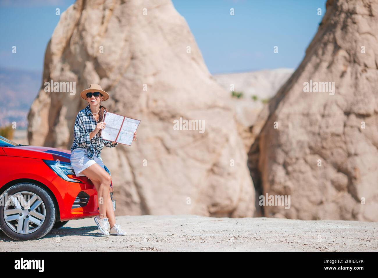 Joven hermosa mujer con mapa de vacaciones en coche en Cappodocia. Formaciones de cuevas. Foto de stock