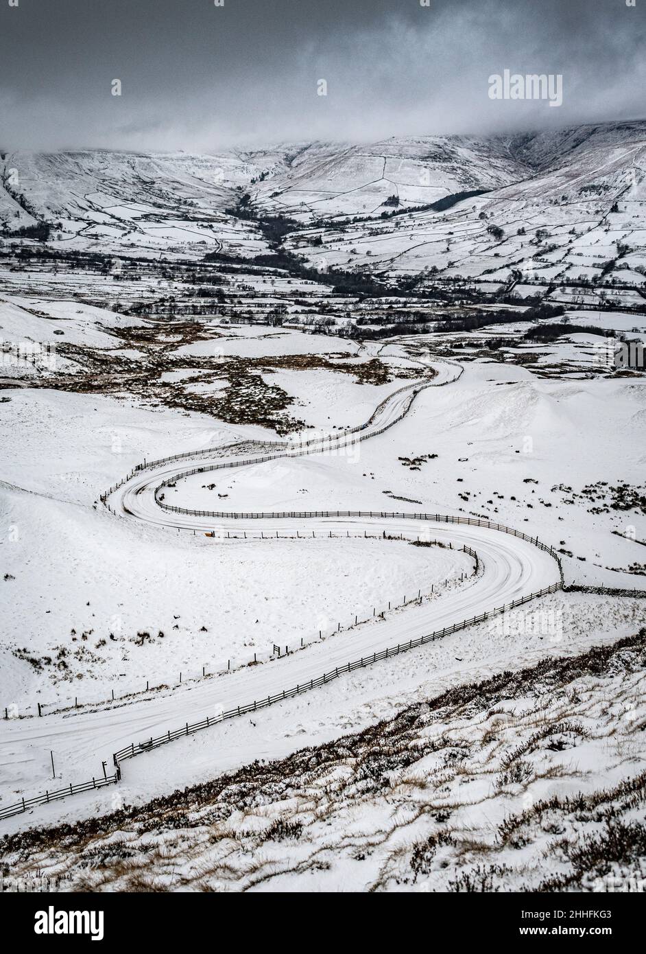 Carretera serpenteante a través de un paisaje nevado con colinas Foto de stock