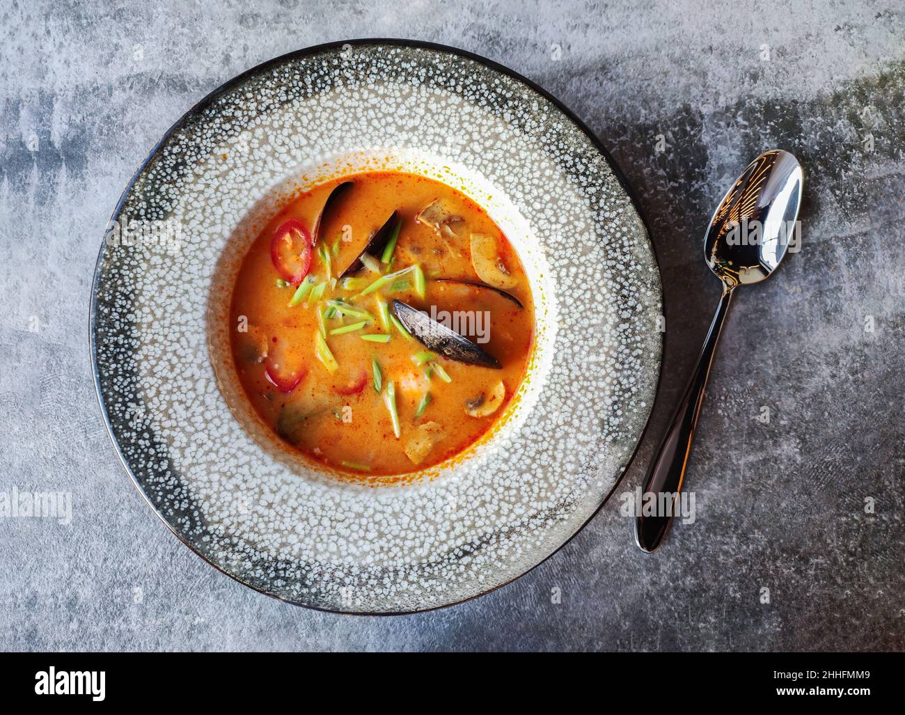 Sopa Tom Yam Kung (cocina tailandesa) con vistas a la mesa del restaurante de piedra gris Foto de stock