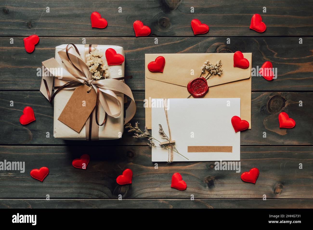 Caja de regalo y tarjeta de felicitación con lazo y corazones de papel en mesa de madera para el día de San Valentín. Espacio para copias. Foto de stock