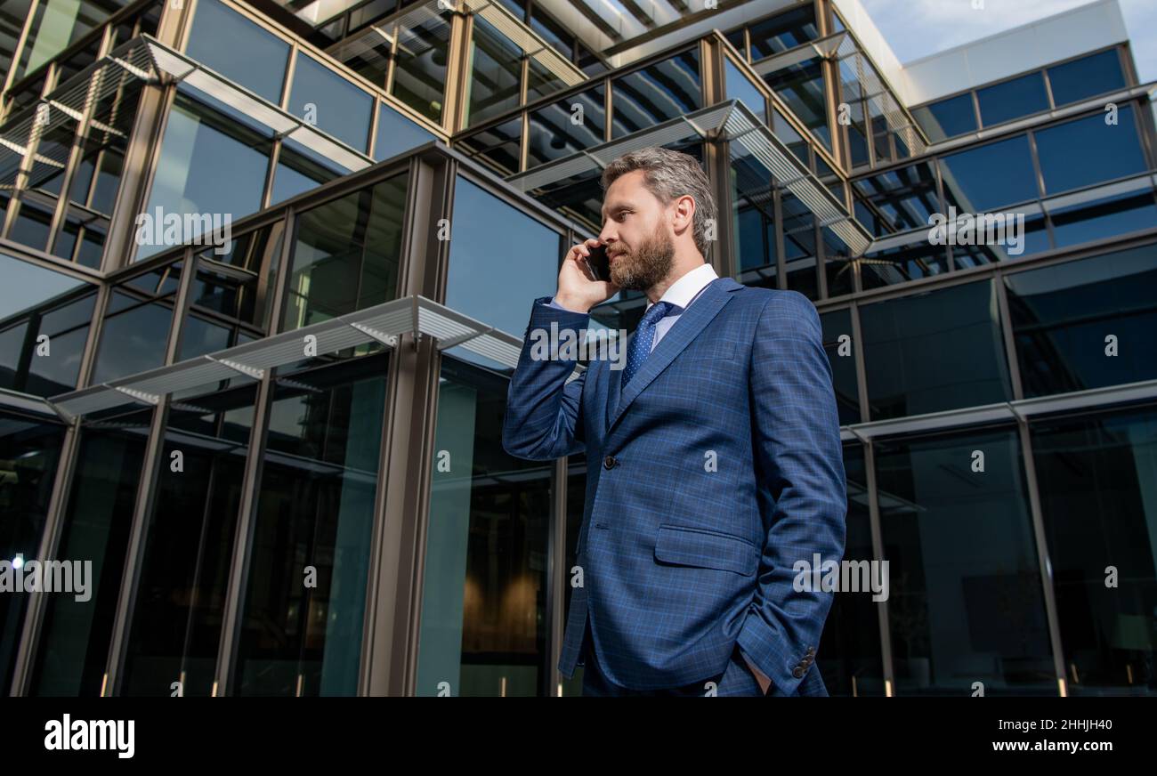 hombre de negocios barbudo con éxito serio en traje formal hablando en smartphone, respuesta telefónica Foto de stock