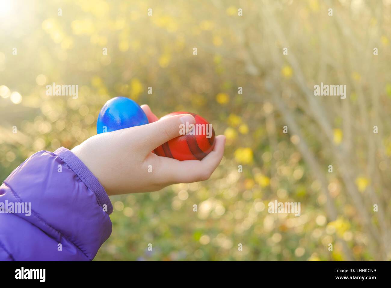 Huevos de Pascua Hunt.Easter Huevos en la mano de un niño en un florido jardín de primavera en el sol. Huevos coloridos. Vacaciones de Semana Santa Tradition.Spring vacaciones religiosas Foto de stock