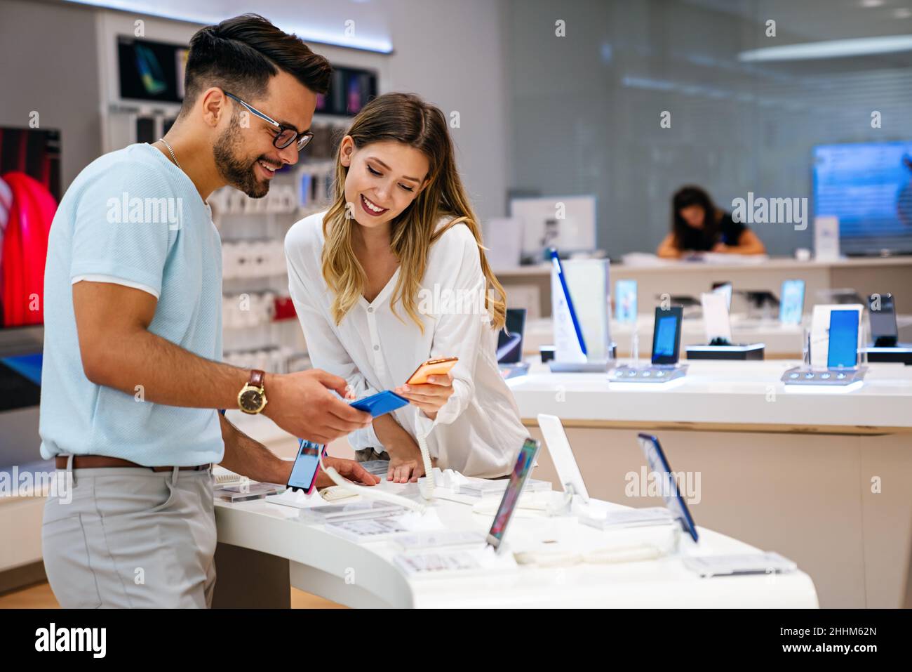 Comprar un nuevo dispositivo digital. Feliz pareja comprando un smartphone en la tienda. Foto de stock