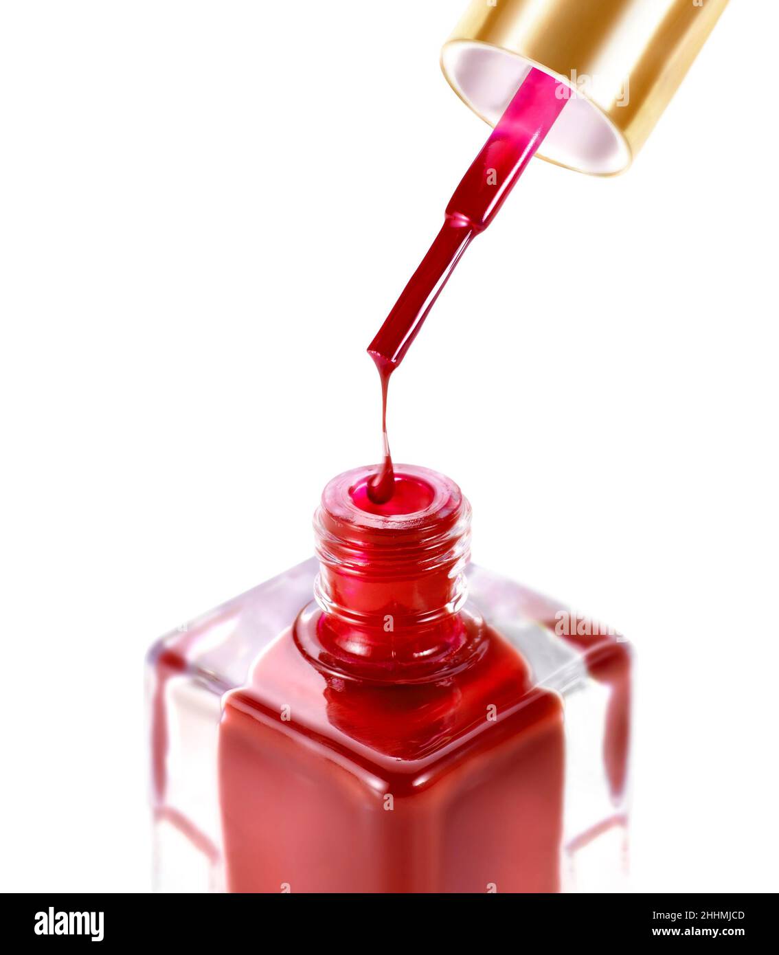 Botella de esmalte de uñas de color rojo y cepillo goteando. Sobre fondo blanco Foto de stock