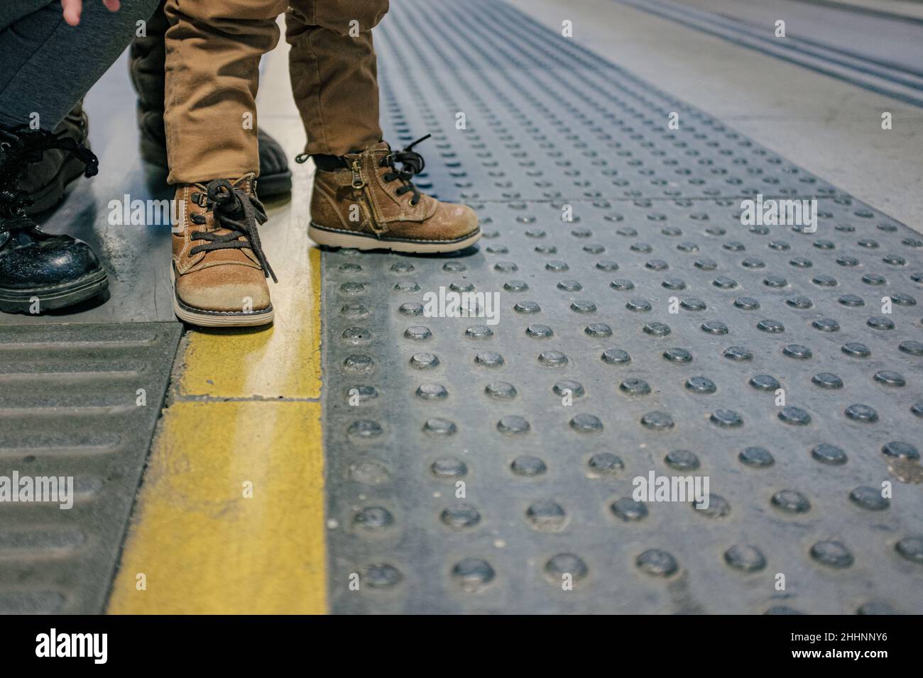 Botas de bebé marrones esperando en una línea de parada amarilla pintada en  el suelo Fotografía de stock - Alamy