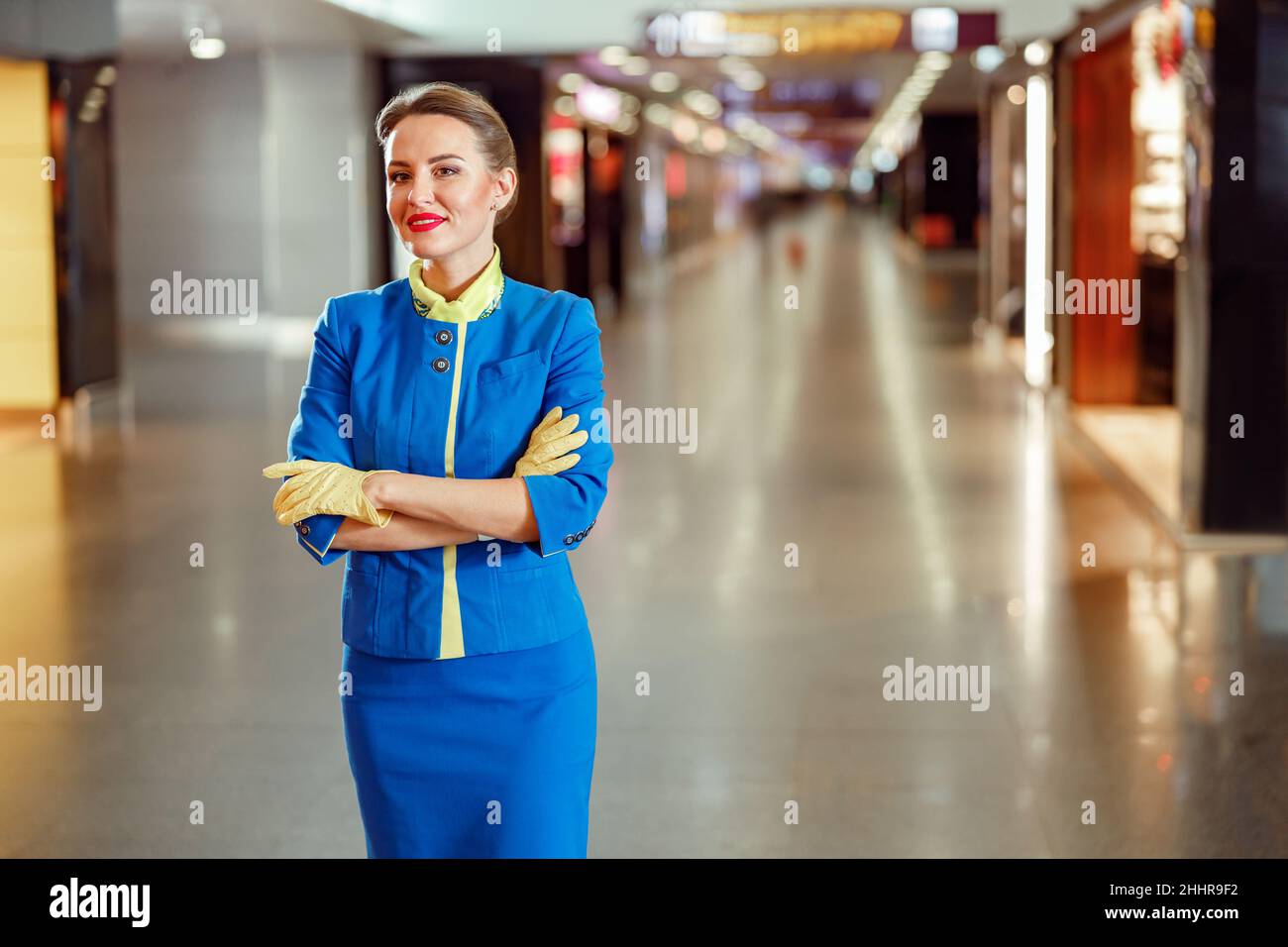 Alegre asistente de vuelo de pie en la terminal del aeropuerto Foto de stock