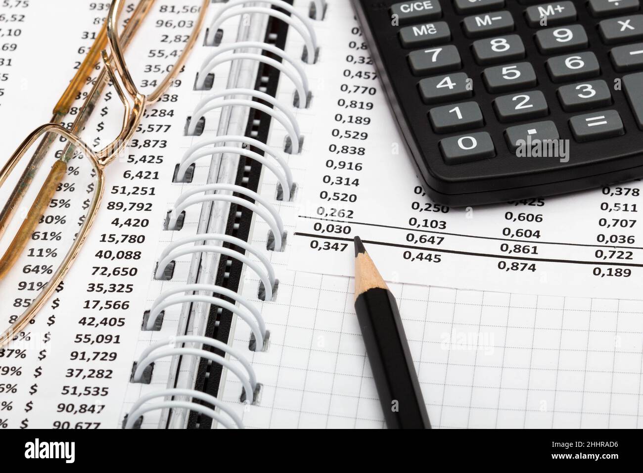 Informe financiero, calculadora, lápiz y vasos en la mesa en la oficina.  Una hoja de papel llena de datos empresariales. Número de cuenta en el  documento de datos Fotografía de stock -