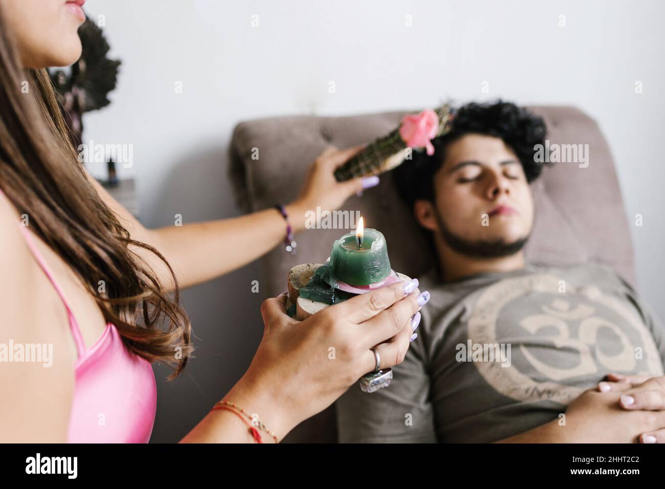 Mujer hispana joven en una sesión de regresión con un hombre joven acostado en el sofá en terapia holística en América Latina Foto de stock