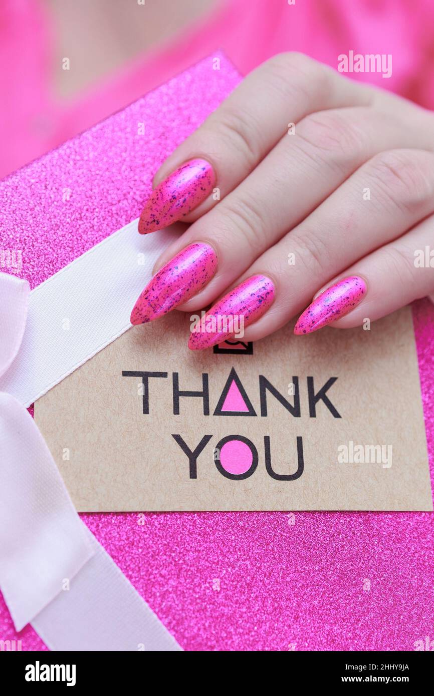 Las manos femeninas con clavos largos y esmalte de uñas rosa neón tienen una  imagen con la inscripción Gracias Fotografía de stock - Alamy