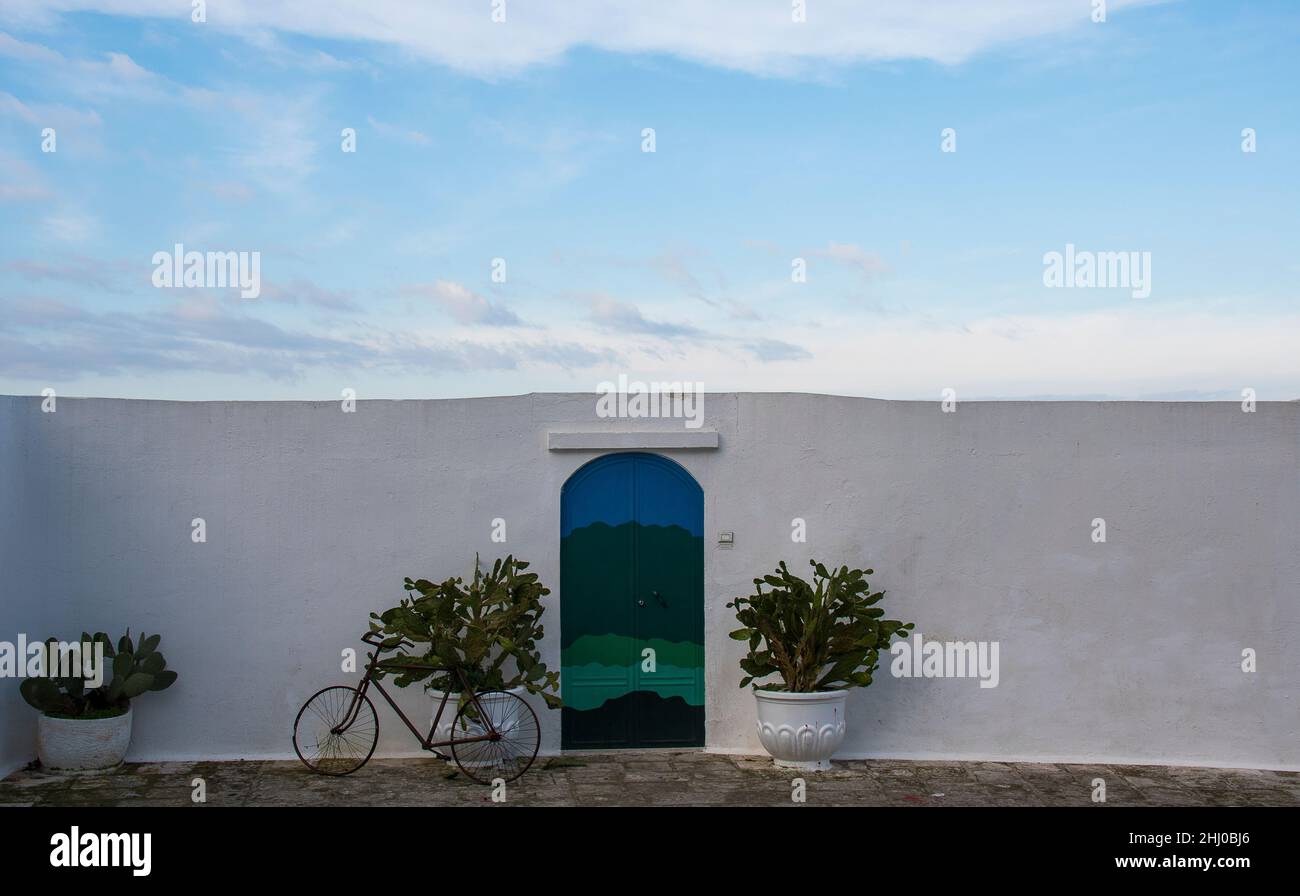 Una bicicleta y dos ollas junto a una puerta colorida y una pared