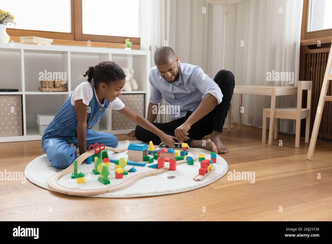 La niña y el padre juegan cubos y ferrocarril en casa Foto de stock