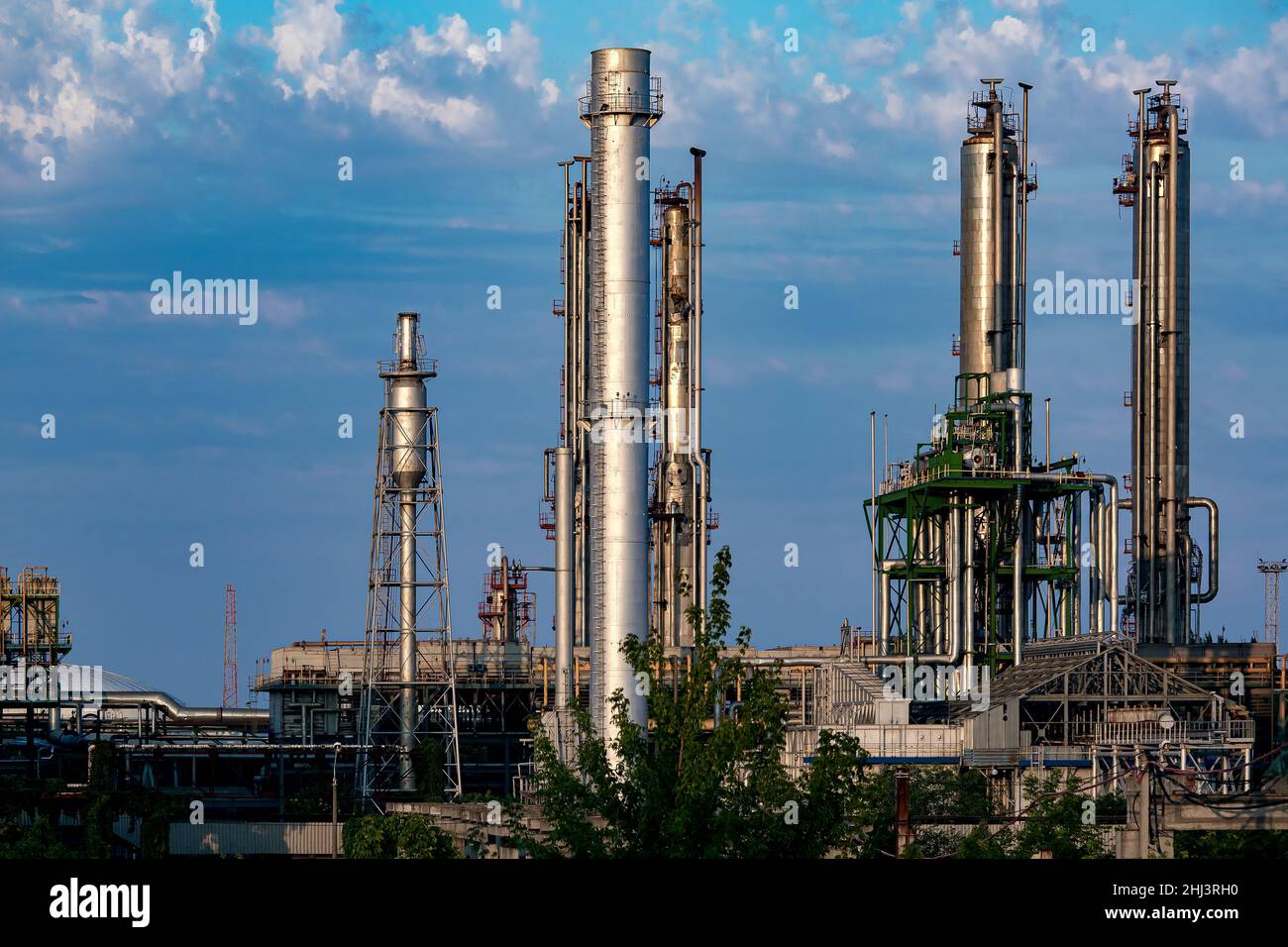 planta industrial con tubos metálicos grises contra un cielo azul con nubes, nadie. Foto de stock