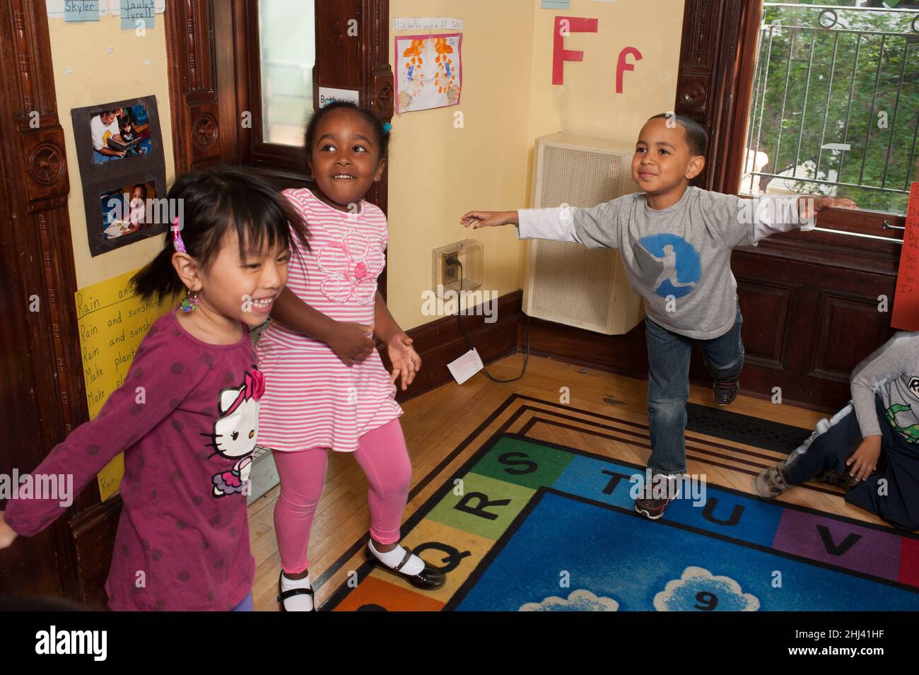 Educación Preescolar Head Start Niños de 3-4 años de edad juegos físicos niños respondiendo a la música, un niño balanceándose en un pie Foto de stock