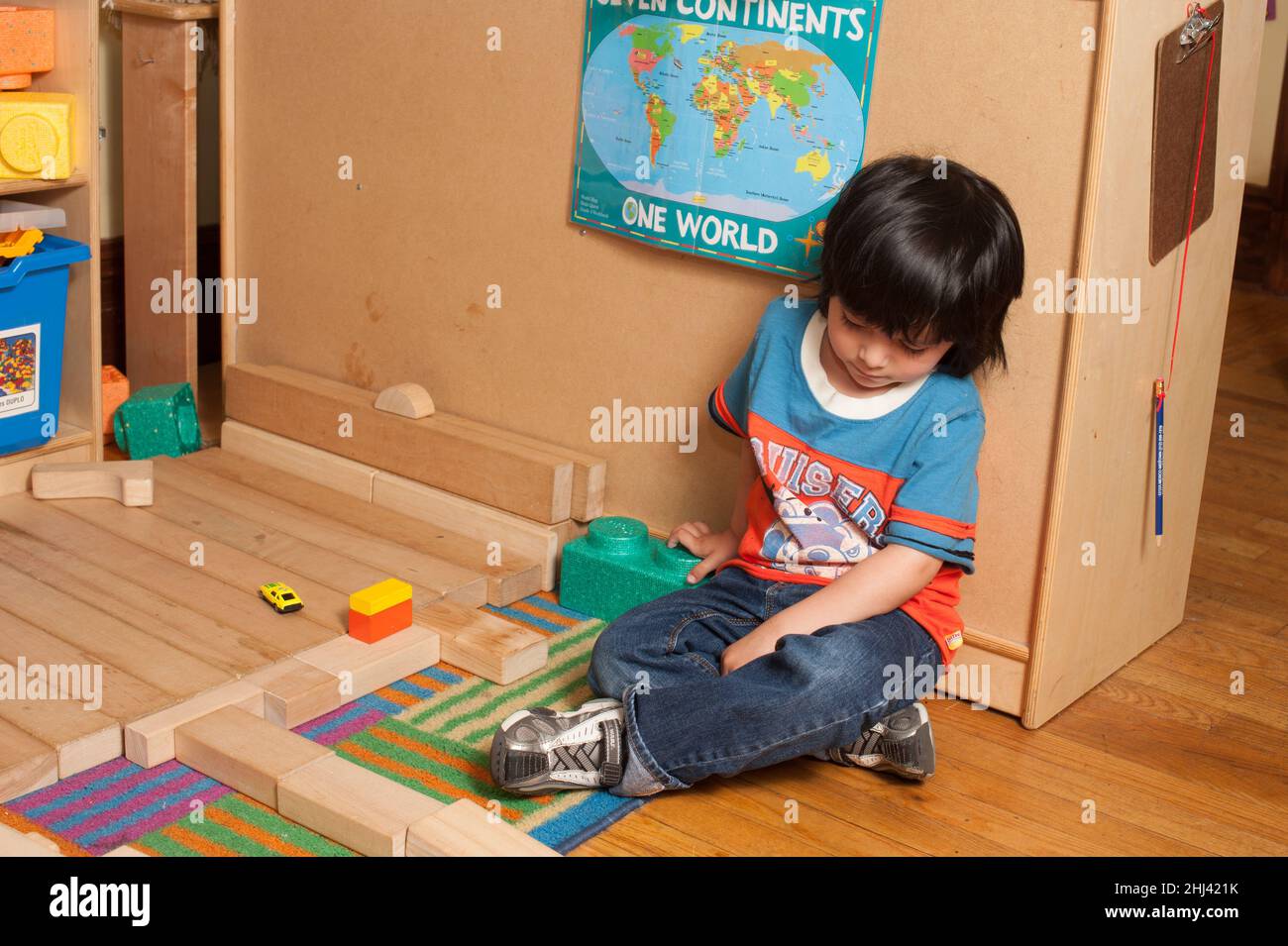 Educación Niño preescolar sentado solo en el salón de clase, tranquilo, retirado Foto de stock