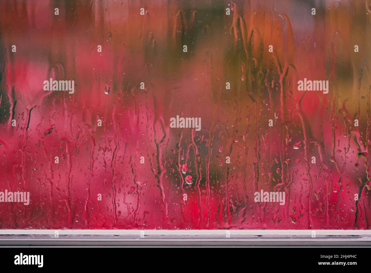 Día lluvioso: Rivulets de agua en la ventana con colores de otoño fuera borrosos en collage colorido por la profundidad de campo poco profunda Foto de stock