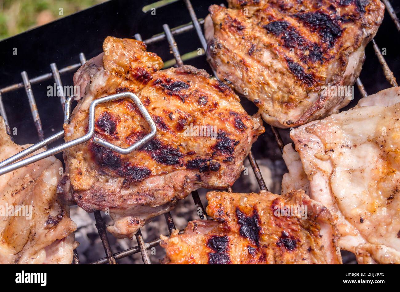 Cocinar pollo, pollo a la parrilla. Cocinar el pollo a la parrilla con carbón en el jardín. Cocina casera, natural. Foto de stock