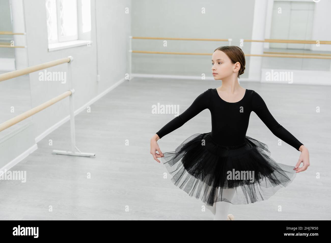 chica con traje de ballet negro haciendo curtsy mientras entrena en el  salón de baile Fotografía de stock - Alamy