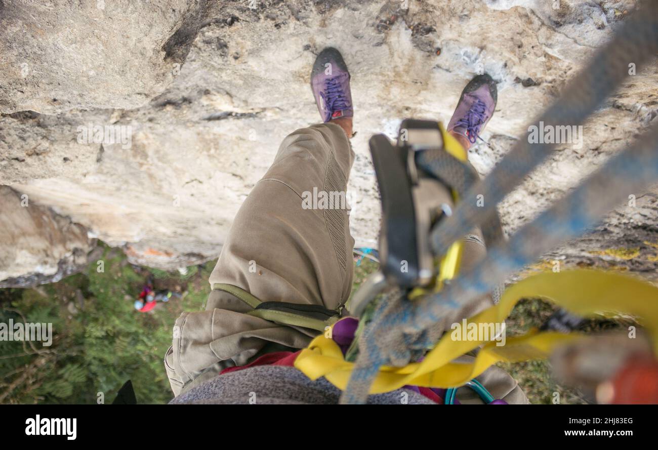 POV: El escalador de la roca cuelga de la cuerda y del engranaje alto sobre el suelo Foto de stock
