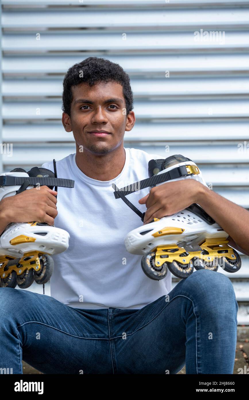 Retrato de un joven latino con confianza que lleva camiseta y patines en línea. Foto de stock