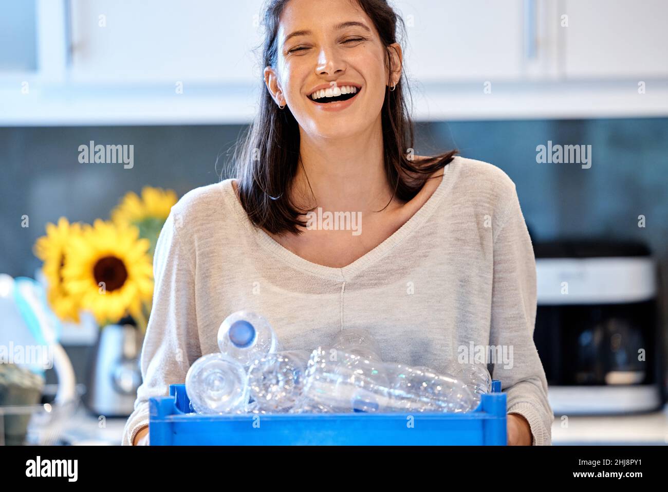 Mamá liderando por ejemplo. Foto de una mujer joven que se prepara para reciclar algunas botellas en casa. Foto de stock