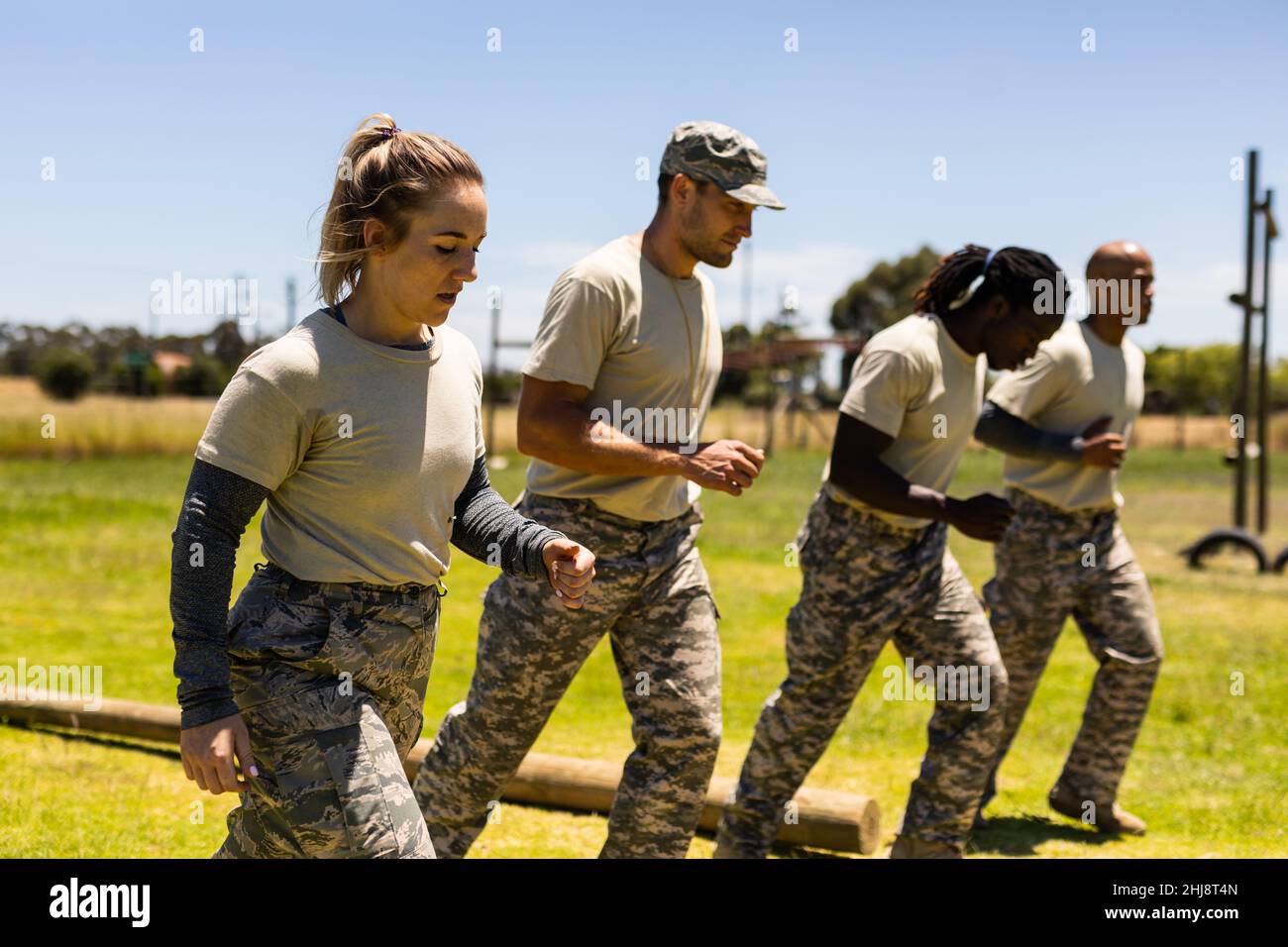 Grupo de hombres y mujeres soldados diversos corriendo juntos en el campo de bota Foto de stock