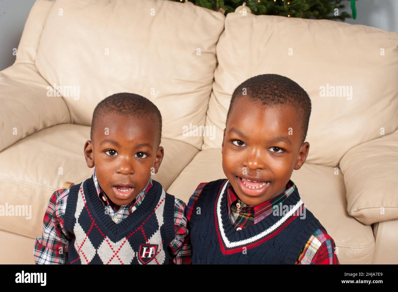 Retrato de dos hermanos en casa, de 2 y 4 años, mirando la cámara, usando jerséis Foto de stock