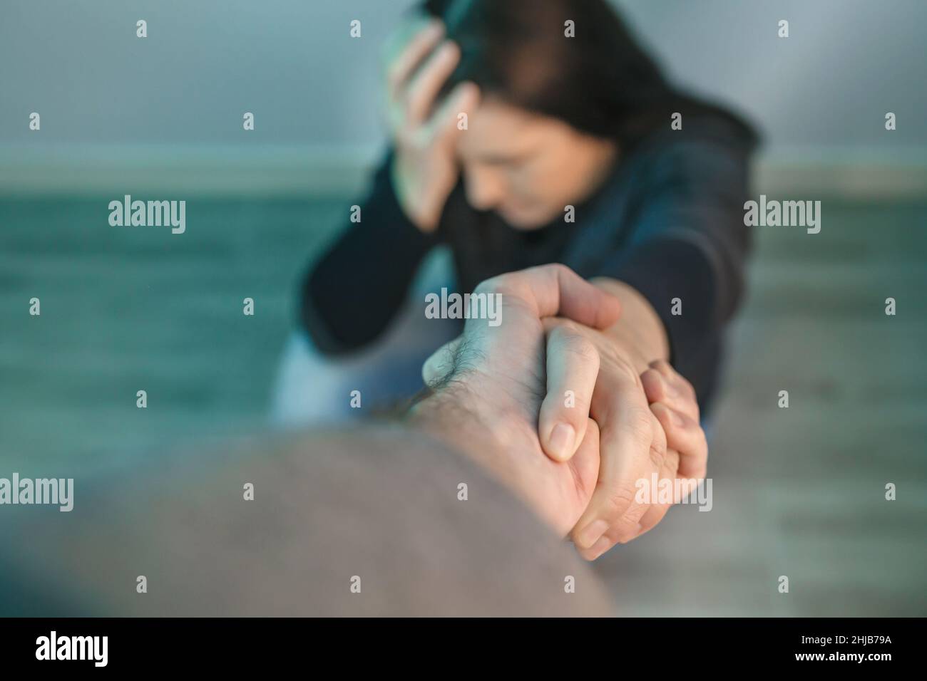 Mujer irreconocible con problemas de salud mental recibiendo ayuda del hombre que sostiene la mano Foto de stock