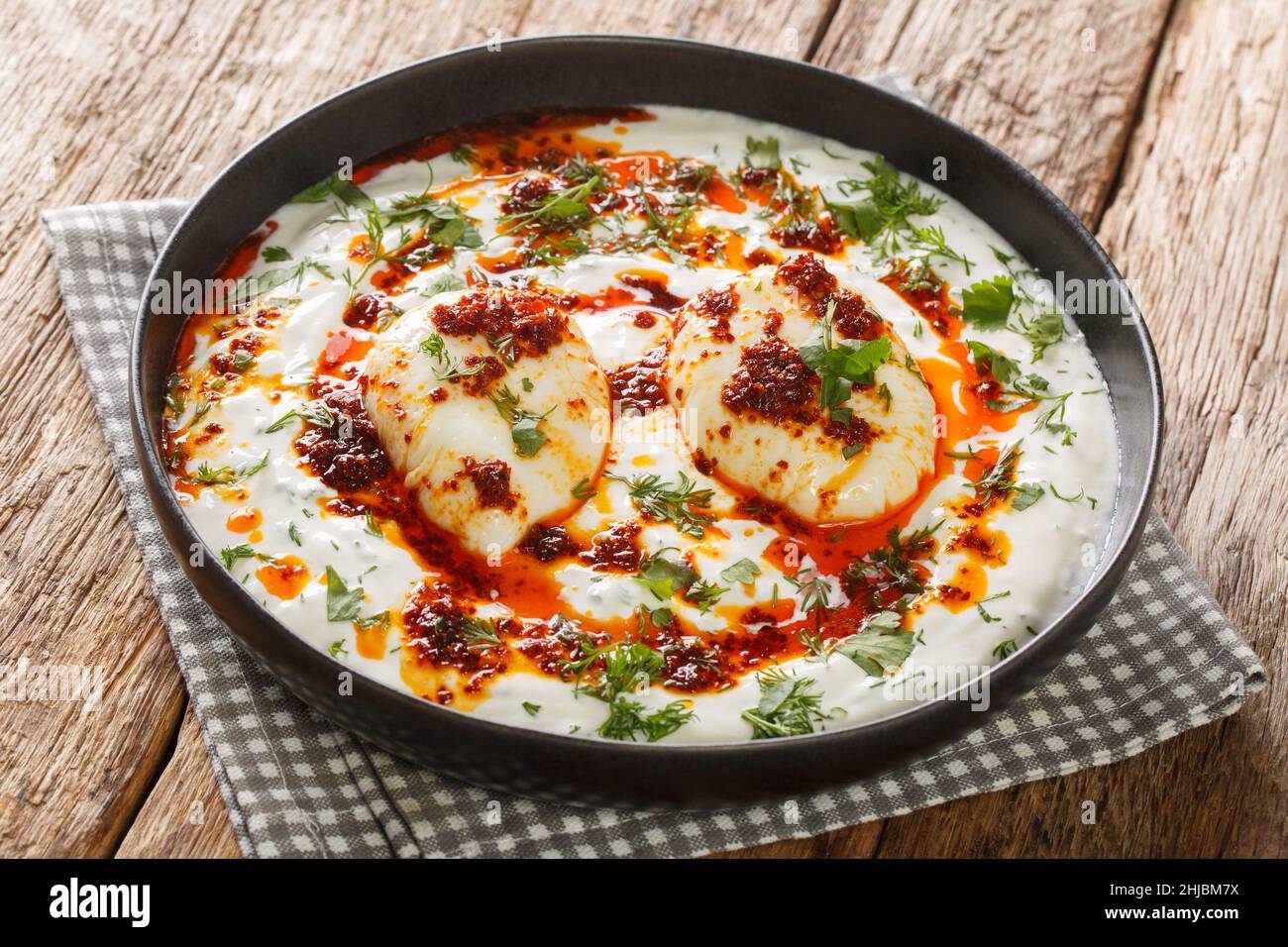 El cilbir es un huevo turco que contiene yogur garlicky, huevos escalfados y mantequilla derretida especiada en el plato de la mesa de madera. Horizontal Foto de stock