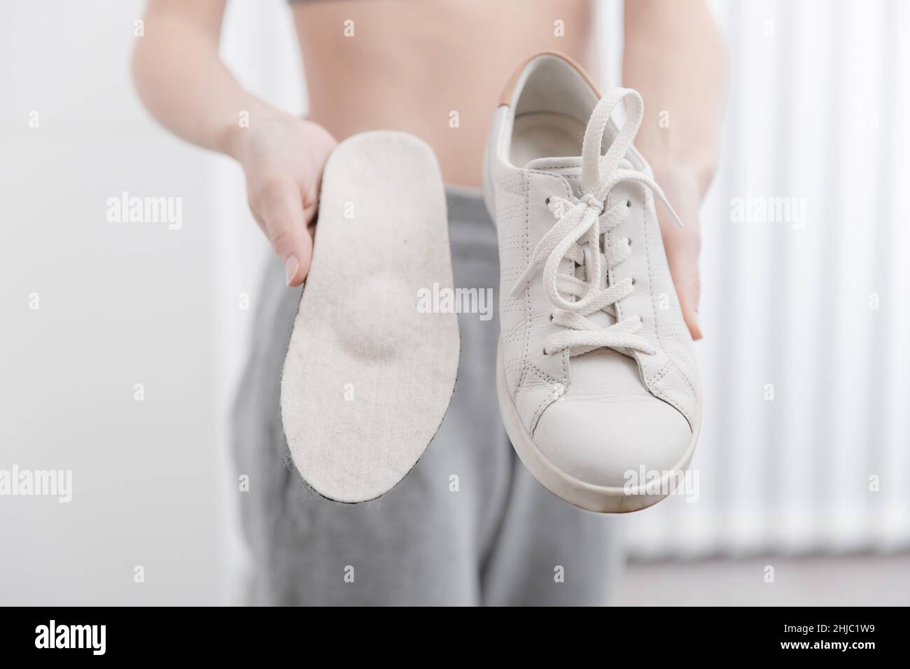 Fitness mujer en ropa deportiva con plantillas ortopédicas y zapatillas de  deporte. Mujer poniendo plantilla ortopédica en el zapato en casa de cerca.  Banner de cuidado de pies. Plana Fotografía de stock -