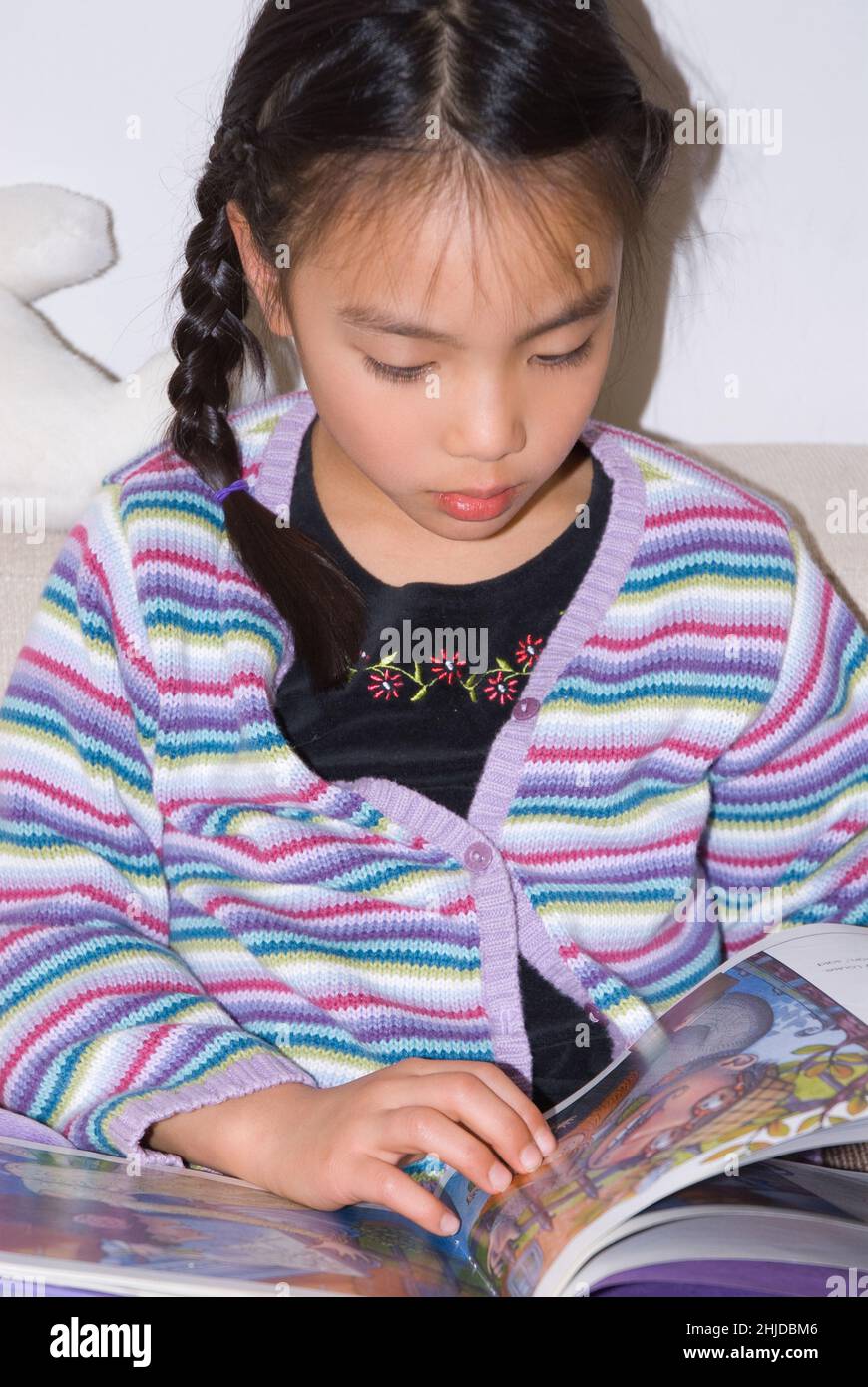 niña de 5 años sentada y leyendo un libro de fotos Foto de stock