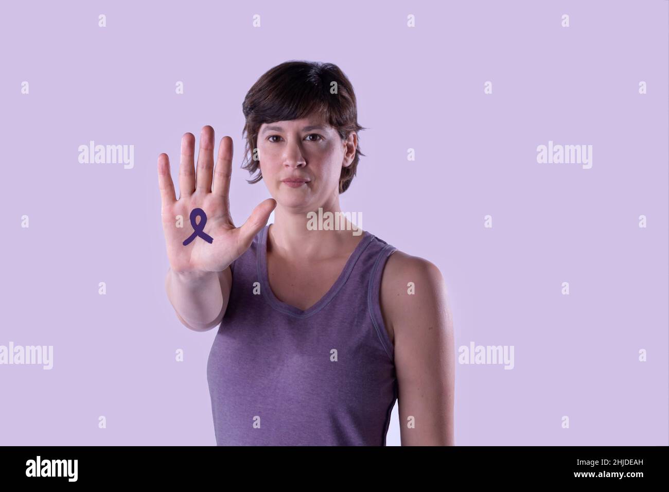 Mujer joven haciendo la señal de freno de mano contra el fondo del estudio lila.Cierre y enfoque selectivo, copia espacio. Concepto de feminismo, igualdad de derechos. Foto de stock