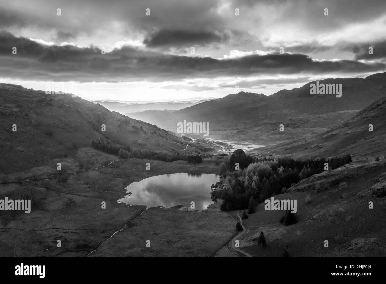 Blanco y negro Epic aérea drone paisaje imagen de la salida del sol desde Bea Tarn en Lake District durante impresionante exposición de otoño Foto de stock