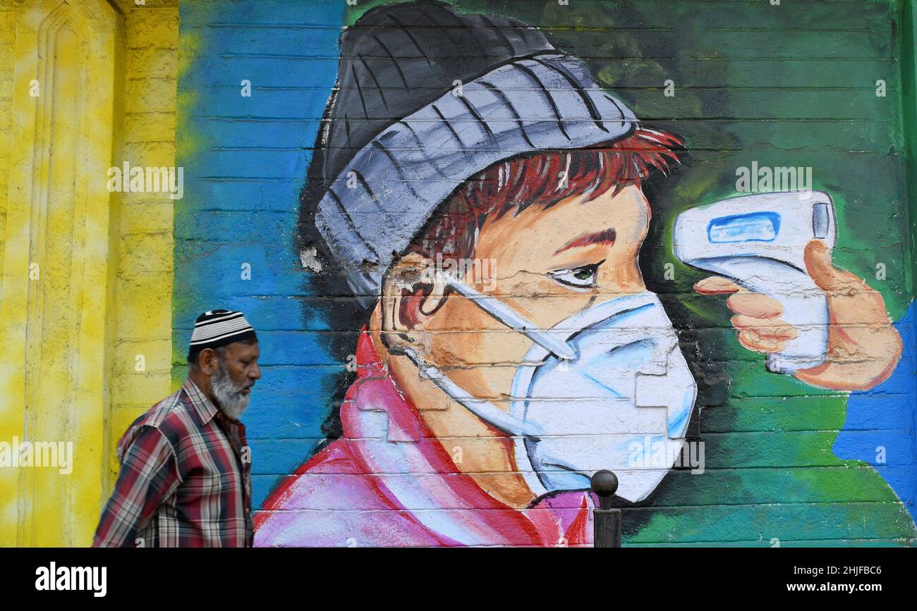 Un hombre musulmán pasa por un graffiti en Mumbai.Los graffiti de  Coronavirus se pintan para crear conciencia y difundir el mensaje sobre el  mantenimiento de la distancia social, el uso de máscaras